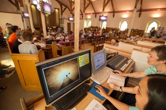 2 women controlling a computer that manages the audio of the sactuary