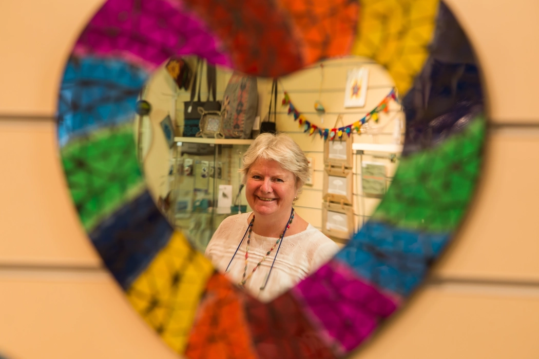 Woman looking through a heart shaped window at the camera